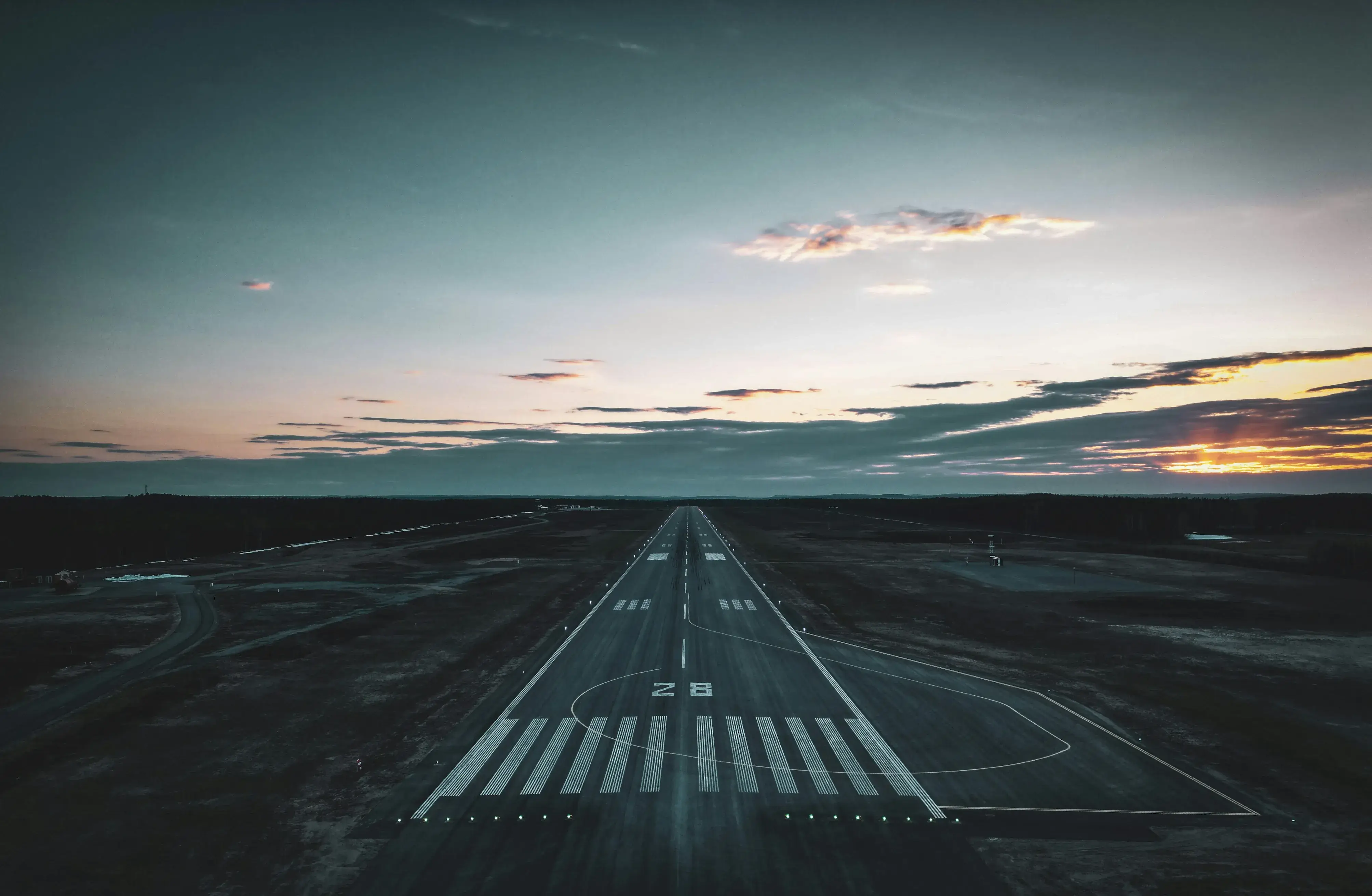 Airport runway with clouds and sunset in the horizon