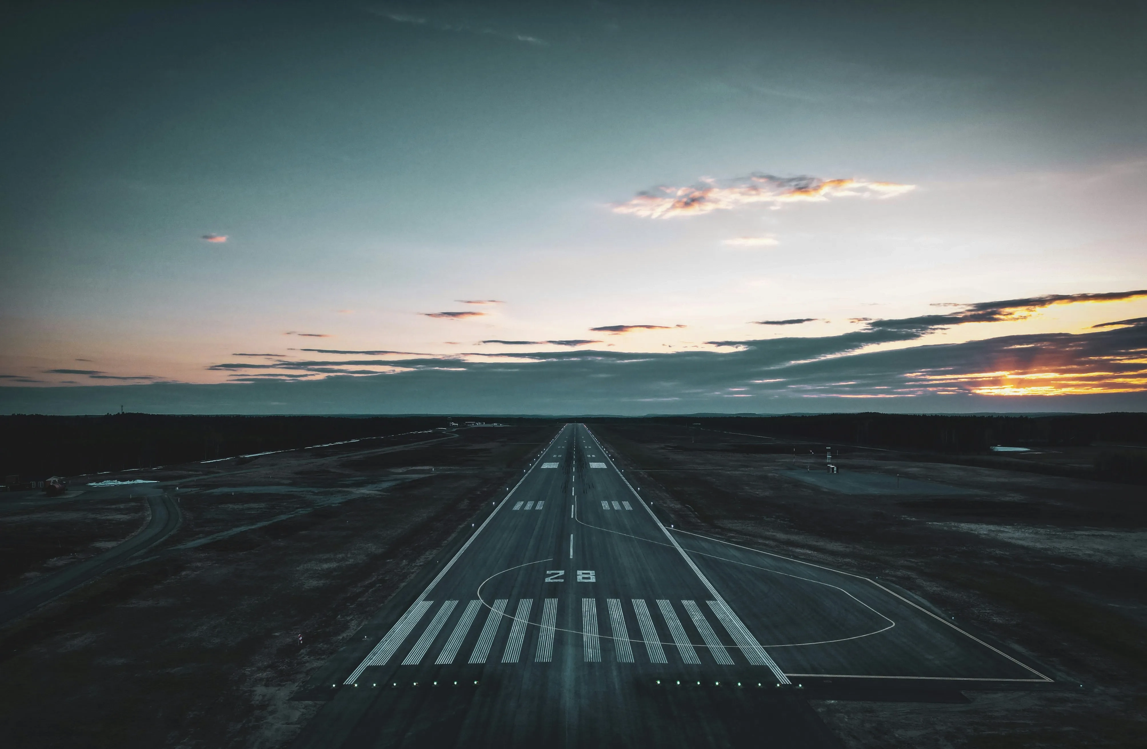 Airport runway with clouds and sunset in the horizon