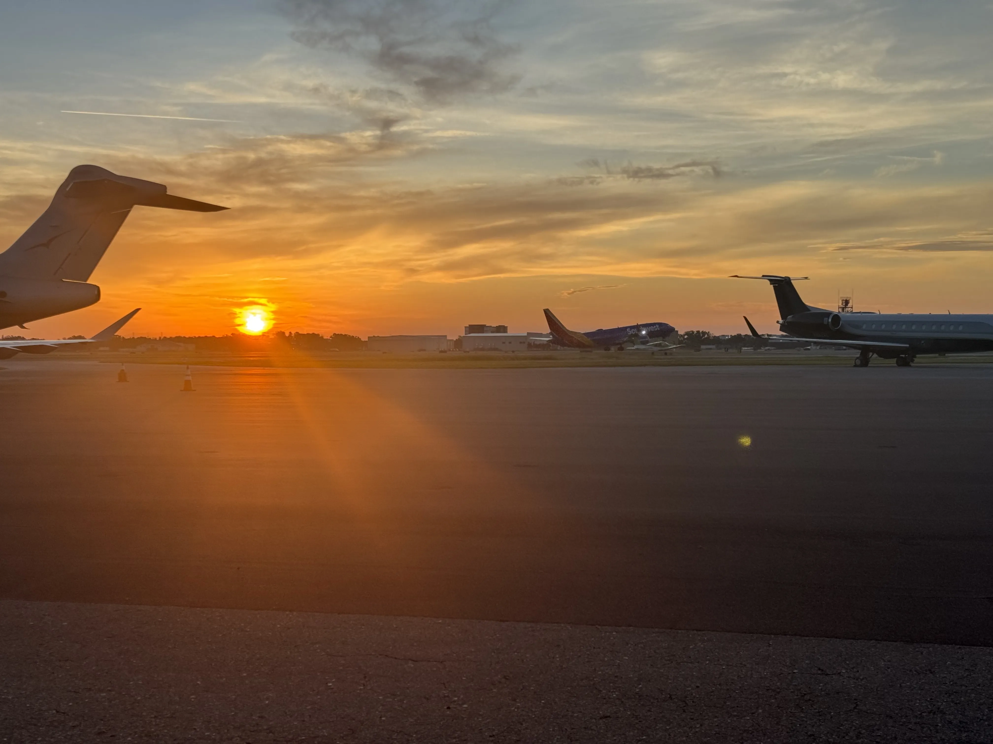 Airport runway with planes in sight and the sunset in the horizon