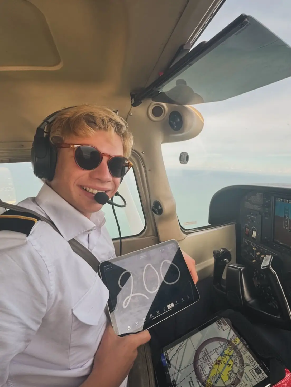 Pilot inside a flying airplane holding a tablet with 200 written on it