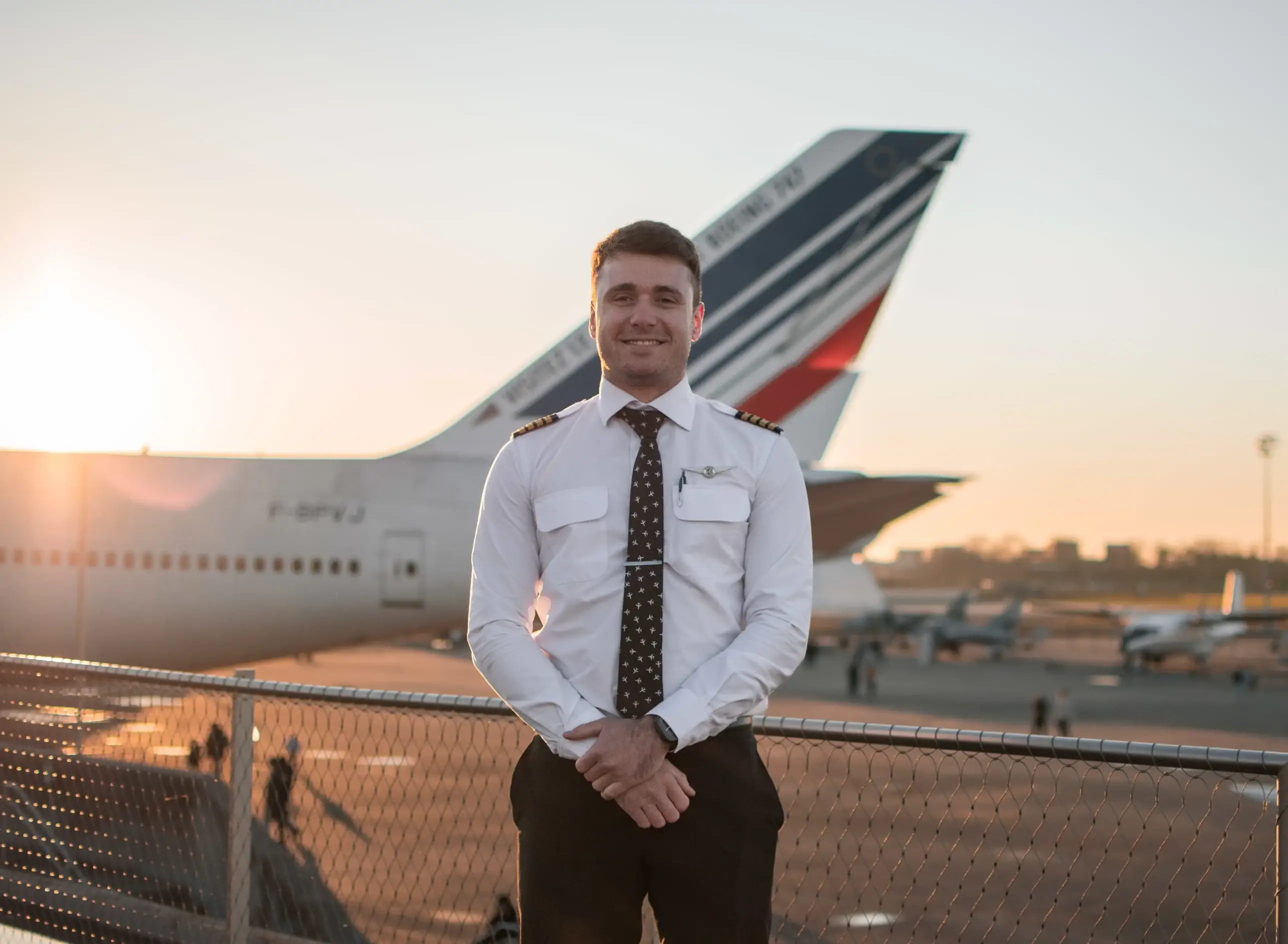 Pilot in front of an airplane's tail smiling to the camera