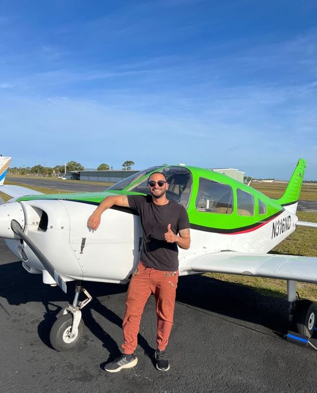 Student standing in front of a Piper Warrior aircraft
