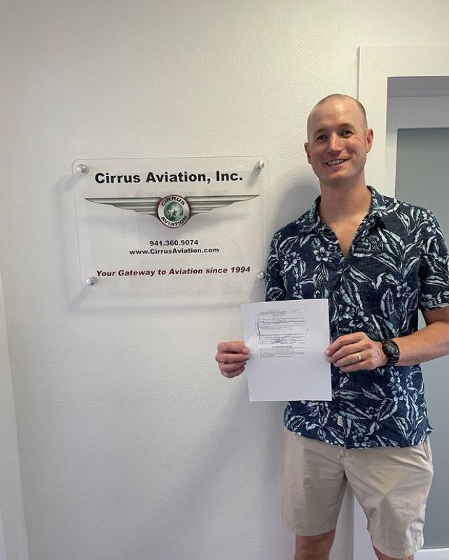 Student holding certificate and smiling at the camera