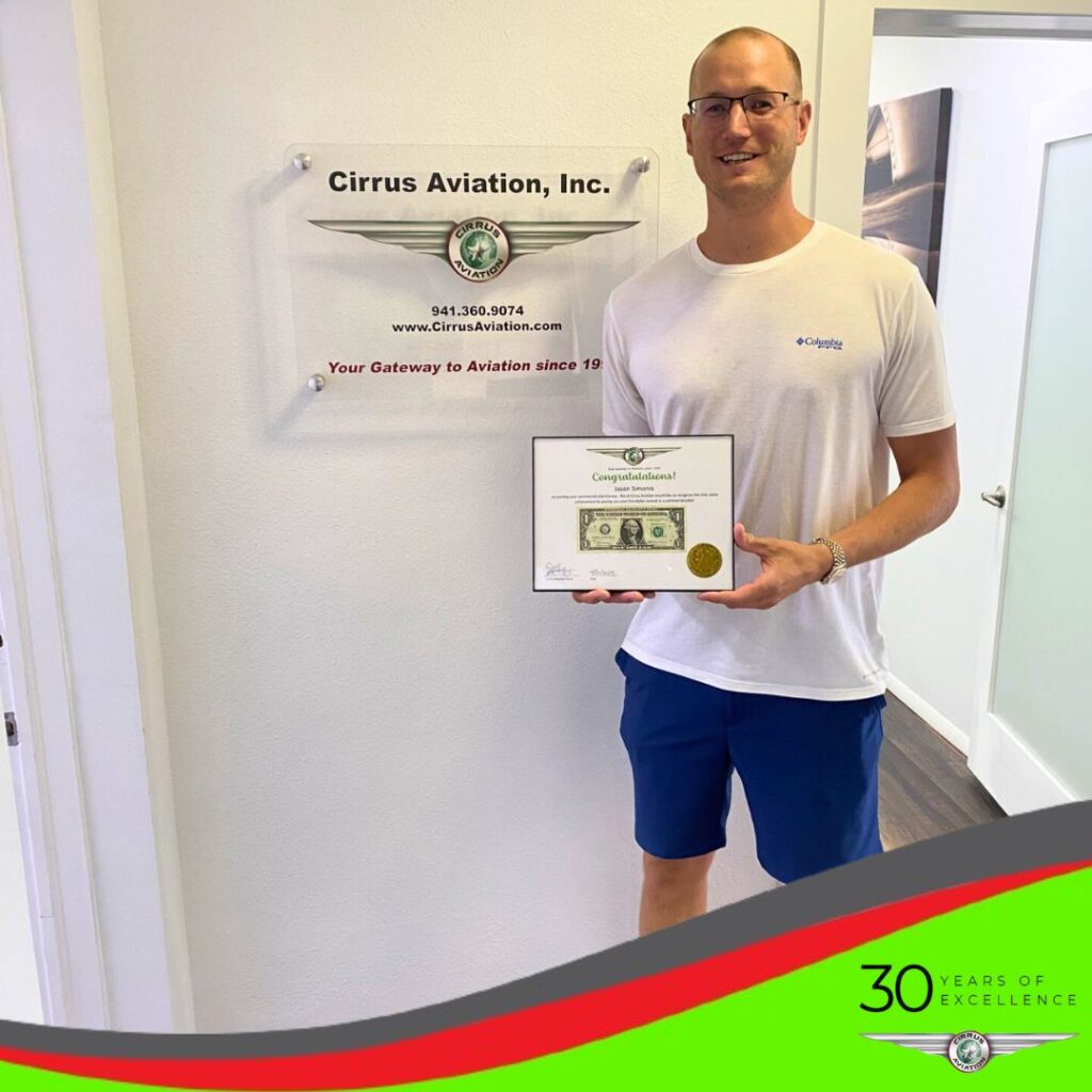 Student holding certificate and smiling at the camera, Cirrus Aviation watermark at the bottom of the image