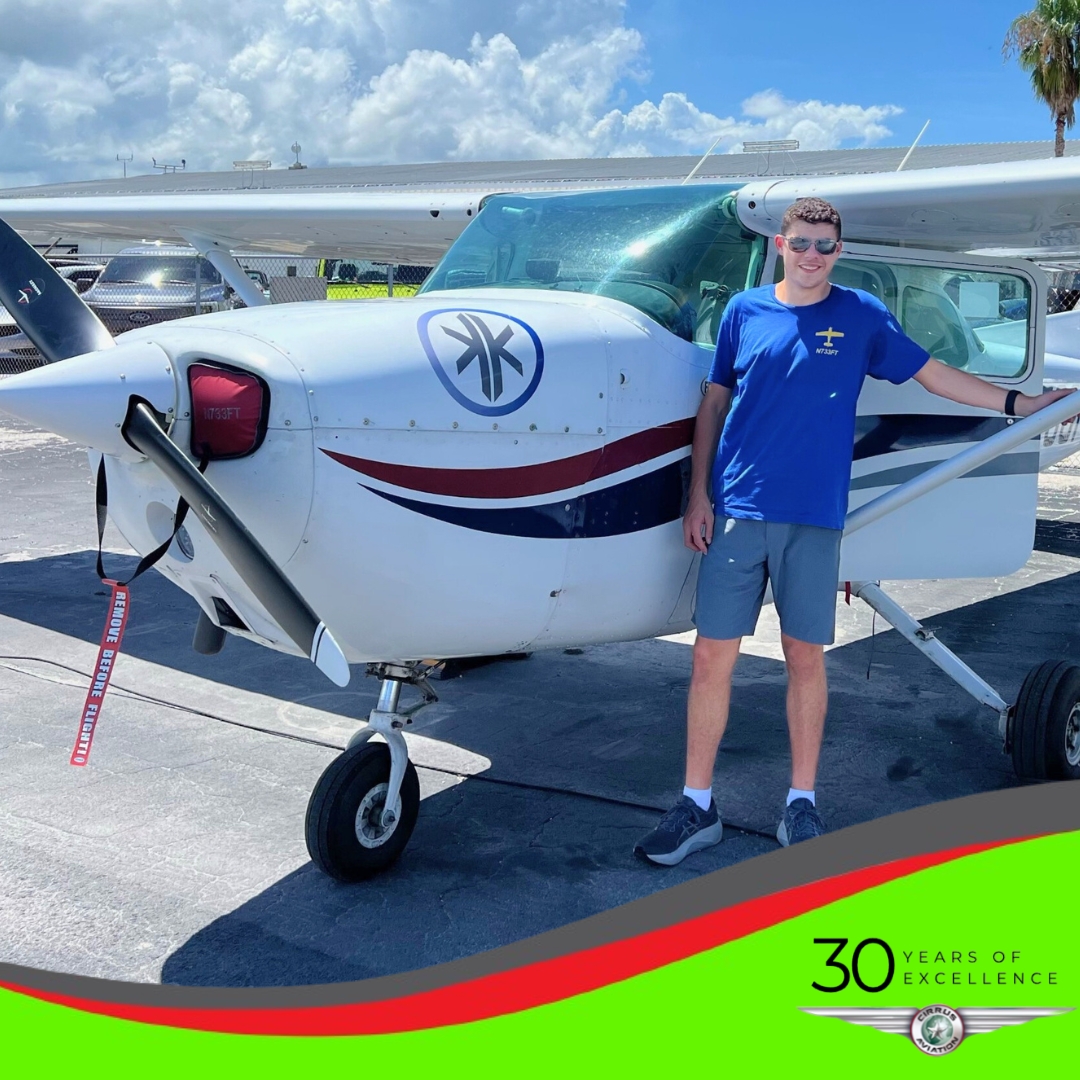 Student standing in front of a Cessna aircraft, Cirrus Aviation watermark at the bottom of the image