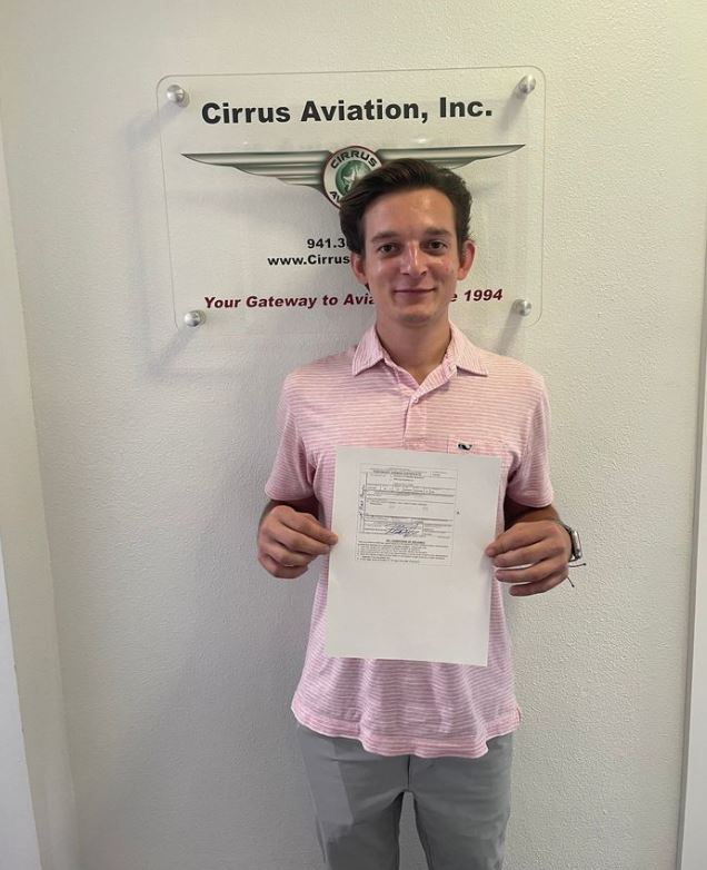 Student holding certificate and smiling at the camera