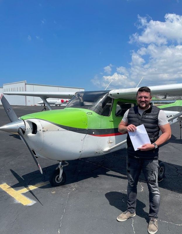Student holding a certificate in front of a Cessna aircraft