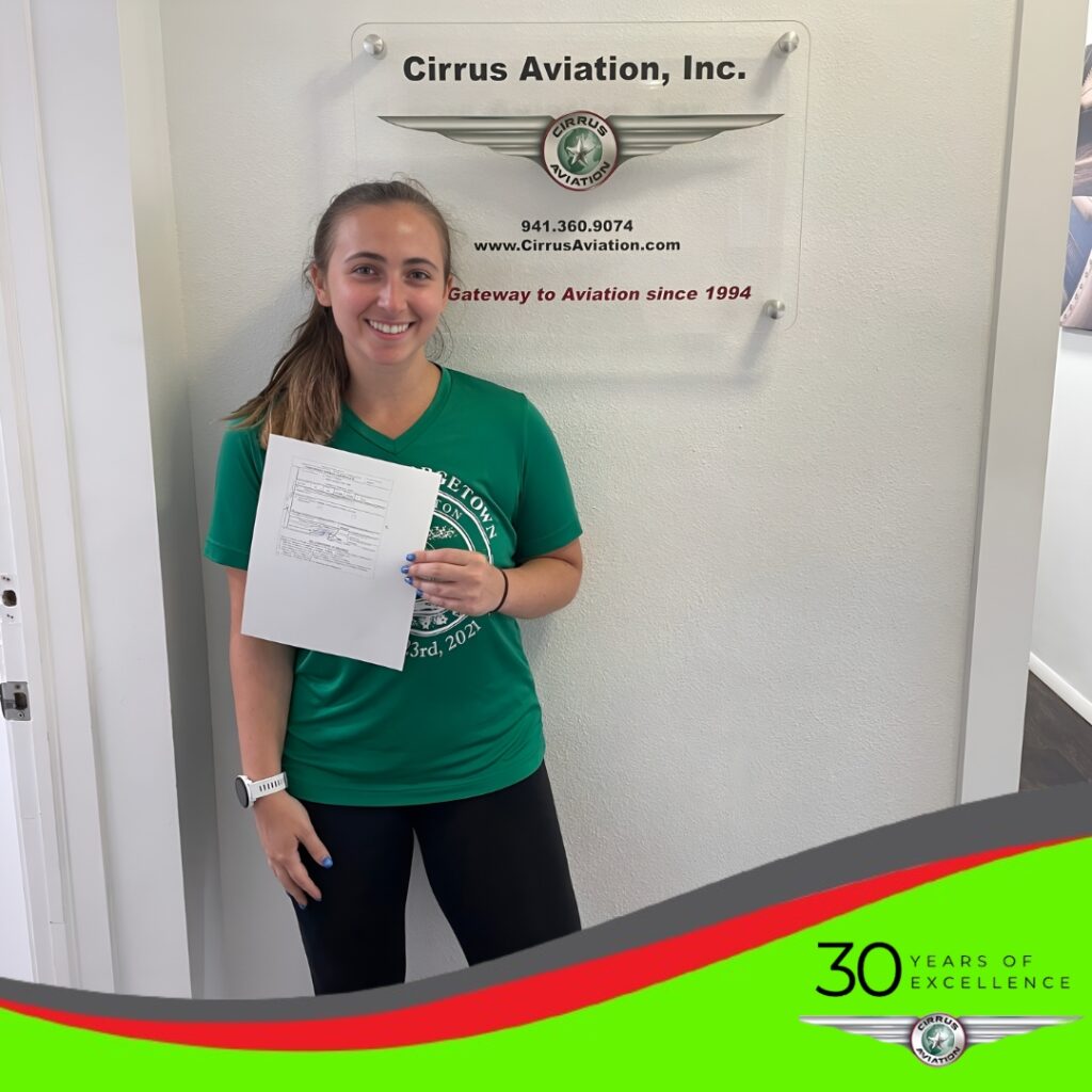 Student holding certificate and smiling at the camera, Cirrus Aviation watermark at the bottom of the image