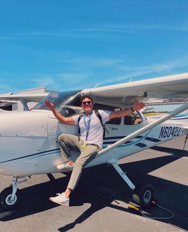 Student with open arms balancing on a Cessna aircraft's left wing