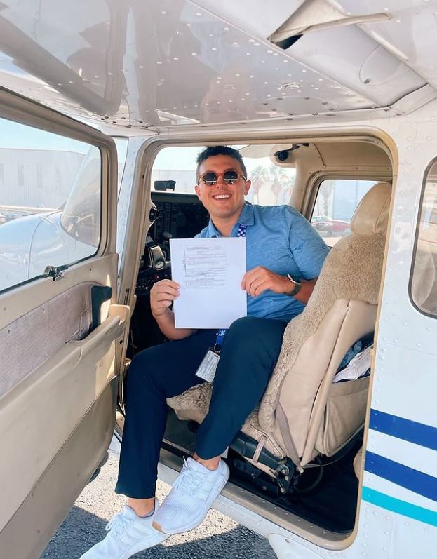 Man holding certificate and smiling at the camera inside an airplane