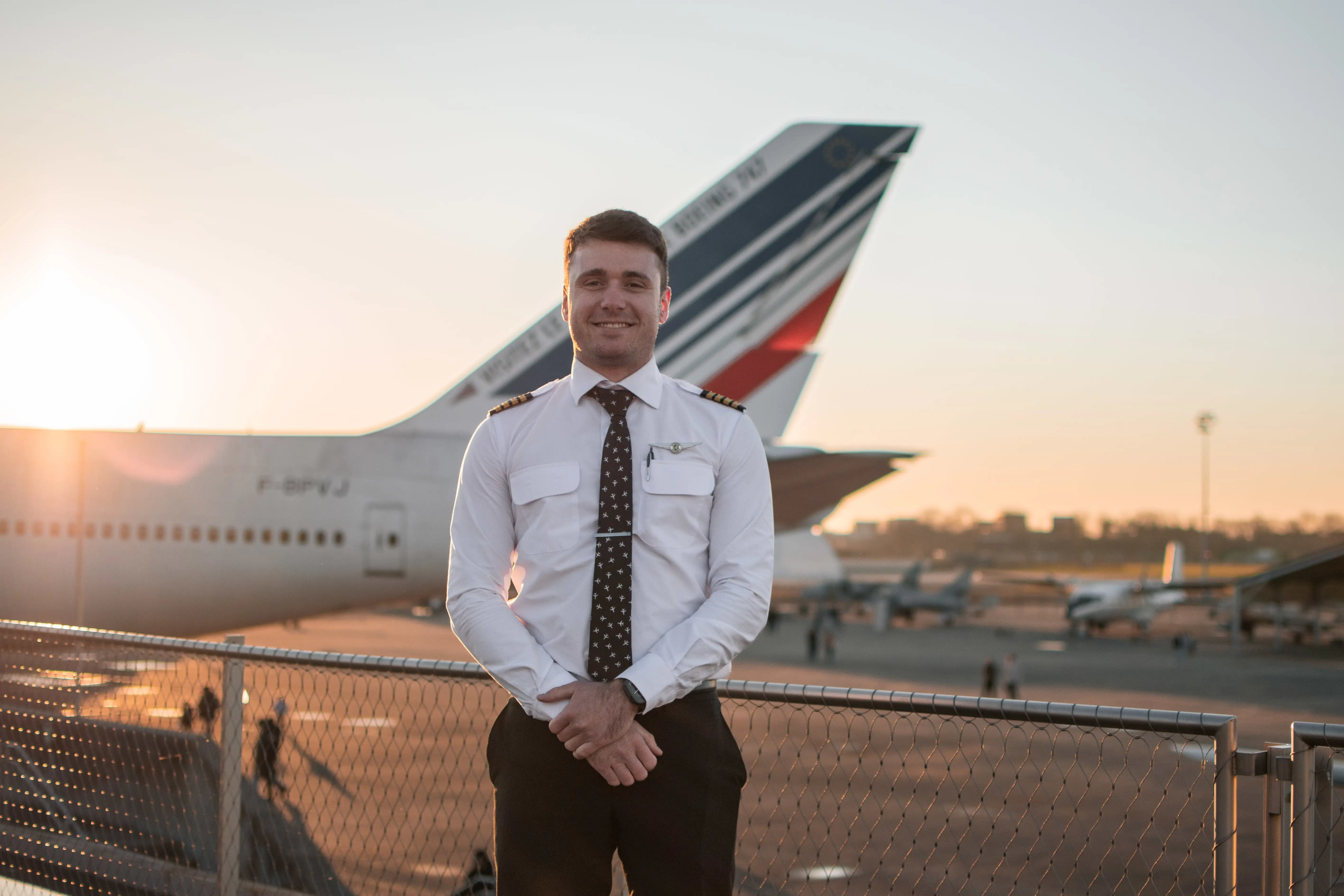 Pilot in front of an airplane's tail smiling to the camera